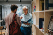 © qunica.com - A student engages in a conversation with a professor in a library, sharing knowledge and ideas. The educational atmosphere promotes learning and mentorship within an academic environment.
