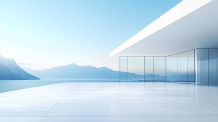 A modern white building with large glass windows overlooking the sea, with a clear blue sky and mountains in the background