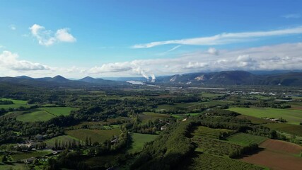 Wall Mural - Mirmande, France - November 1, 2024: Panoramic view of the surrounding mountains in Mirmande and steam coming out of the chimneys of the Cruas Nuclear Power Plant in the distance