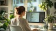 © Elena - A woman works on a computer surrounded by houseplants in a bright home office during the morning hours