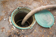 © Sergey - Pumping sewage. A vacuum hose extends into a green sewage tank, ready to extract waste. drainage system.