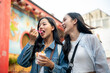 © bongkarn - Two joyful Asian female friends explore the city in Chiang Mai, Thailand, enjoying ice cream.