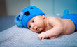 © Vadim - Baby in blue hat and diaper on blanket. A cute baby lays on a soft blanket, wearing a blue knitted hat and diaper, gazing curiously at the surroundings.
