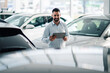 © Zamrznuti tonovi - Businessman reviewing car information on a tablet in showroom