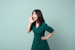 © Jirawatfoto - Happy Asian woman shouting above green dress poses against green background blank copy space for advertising content promotion