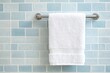 © ali - Fluffy white towel hanging on chrome rack against beige and light blue tiled wall in clean bathroom