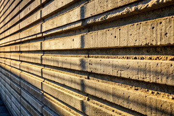 Sticker - Brutalism Textured concrete wall with horizontal lines and warm sunlight casting shadows, creating a visually striking pattern.