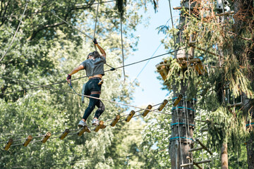 Wall Mural - a woman skillfully navigating a challenging tree climbing course while surrounded by vibrant and lus