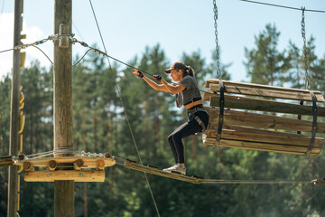 Wall Mural - a woman navigates a thrilling rope course, showcasing balance and agility in an outdoor adventure pa
