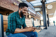 © Dusan Petkovic - Smiling young multicultural traveler sitting on train station and typing messages on a phone.