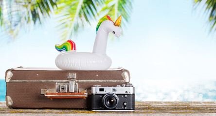 Poster - A bag with travel stuff, camera, and floating flamingo placed on a table