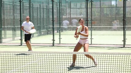 Wall Mural - Young woman and young man playing doubles padel tennis on tennis court