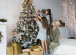 © Tatsiana - A heartwarming family moment as a grandmother and her two granddaughters decorate a beautifully decorated Christmas tree. The warm glow of lights and the festive spirit fill the room