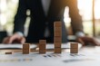© taelefoto - Businessman Analyzing Growth Data with Wooden Cubes on the Table Representing Financial Trends and Success in a Corporate Environment