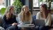 © PhotoStar - Three girls are sitting on a couch and smiling at each other. One of them is holding a laptop