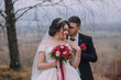 © Vasil - A bride and groom are standing in a field, with the bride holding a bouquet of flowers. Scene is romantic and intimate, as the couple is embracing and looking into each other's eyes