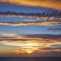 Wall Mural - A high-resolution ultrarealistic image of a serene sunset sky, captured in high-quality digital photography. The expansive sky features a blend of warm and cool tones; soft pastel oranges and yellows 