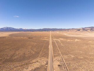 U.S. Route 50, the loneliest road in the USA, aerial view towards snowcapped mountains. Empty road and clear blue sky.