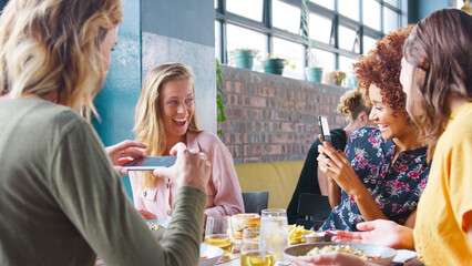 Wall Mural - Group Of Young Female Friends Taking Photos Of Food In Restaurant To Post On Social Media