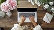 © Aino Minako - A woman is typing on a laptop in front of a vase of pink flowers