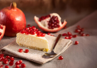 Wall Mural - Slice of delicious cheesecake with pomegranate seeds topping on table