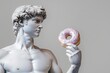 © mikita - White marble statue holding a doughnut with bright appetizing glaze, a fashionable glamor photo concept