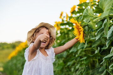 Poster - Child in a field of sunflowers. Selective focus.