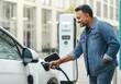 © Alexandra - Happy indian mature man charging electric car at charging station in the city
