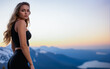 © Evgenii Starkov - Portrait of young attractive woman in sport black leggings and black top with long hair posing on high mountain with stunning view.