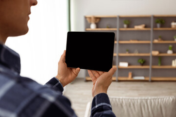 Poster - Guy Holding Digital Tablet Computer With Blank Screen Over Living Room Background Standing Indoors. Designer Using Interior Design Application. Gadget, Technology Concept. Mockup