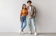 © Prostock-studio - Full length portrait of happy young Asian couple in casual clothes hugging and looking at camera against white studio wall. Cheerful millennial spouses posing and smiling together