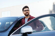 © Maria Vitkovska - Handsome car owner, bearded Latin man wearing stylish eyeglasses, looking away, standing near car
