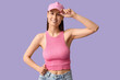 © Pixel-Shot - Beautiful young woman in stylish pink cap on lilac background