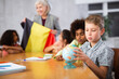 © JackF - Friendly female teacher working in a high school tells pupils the history of Belgium in class and holds the national flag of .the country in her hands