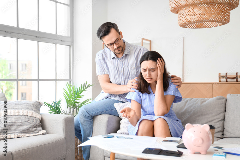 Young man calming down his upset wife at home. Bankruptcy concept