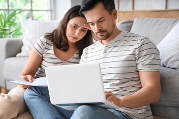 Wall Mural - Young couple using laptop to pay bills at home. Bankruptcy concept