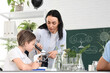 © Pixel-Shot - Teenage boy looking through microscope with teacher in Biology class at school