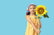 © Pixel-Shot - Cute little Asian girl with beautiful sunflower on blue background