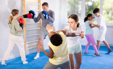 Wall Mural - Girls and boys learns to do power grip with trainer during a self-defense lesson in the gym