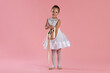 © New Africa - Little ballerina with pointe shoes on pink background