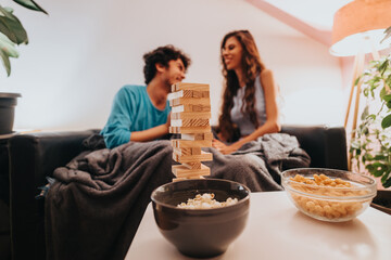 Wall Mural - A cozy scene of a couple enjoying a fun game night at home, surrounded by snacks and a warm atmosphere. Perfect for concepts of leisure, bonding, and relaxation.