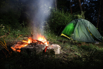 bonfire and camping tent in forest at night