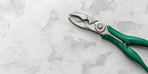 Aufkleber - Pliers with a green handle on a white-painted gray concrete background, toned. Close-up, copyspace, banner format.