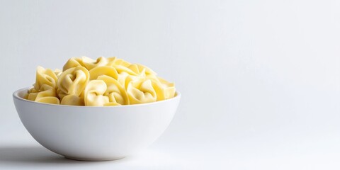 Aufkleber - Fagottini tortellini pasta in a white bowl set against a white background, softly lit, studio shot, angled view, copy space.