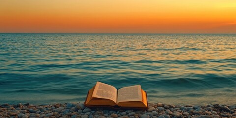 Poster - Bible placed on small stones in front of the green sea under an orange sky. Copy space.