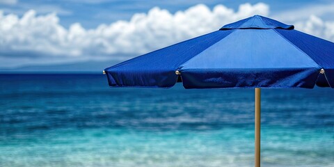 Poster - Close-up of a blue beach umbrella with the sea in the background.
