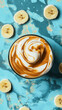 © Wintakorn - Colorful dessert featuring swirl of peanut butter and banana in parfait glass, surrounded by banana slices