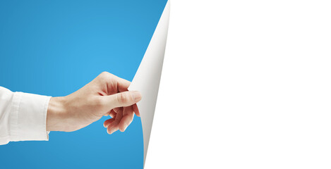Poster - A hand holding and turning a blank white sheet of paper, with a blue background on the left side and white space on the right. Concept for layout