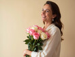 © zamuruev - A mother cradles a bouquet of pink and white roses, her warm smile illuminated by soft light against a light background