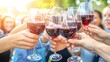 © thesweetsheep - Cheers with red wine glasses at a joyful outdoor gathering.